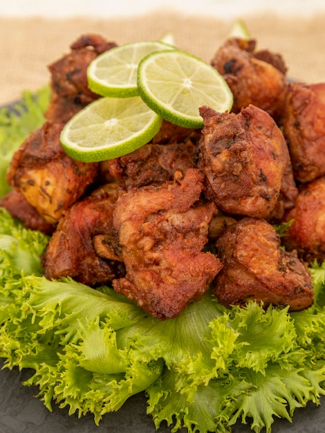 Porzione di pollo fritto su lastra di pietra nera.