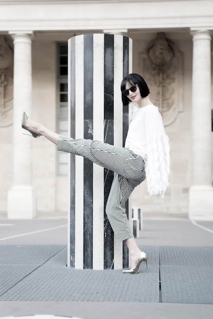 Posa della donna su scarpe tacco alto a Parigi, Francia Donna in occhiali da sole con capelli castani