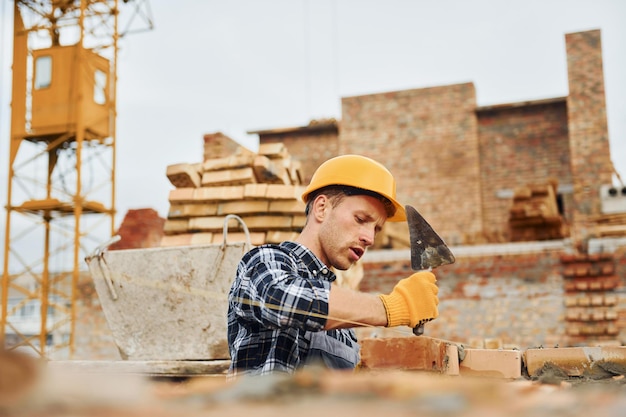 Posa di mattoni Lavoratore edile in uniforme e equipaggiamento di sicurezza ha un lavoro sulla costruzione