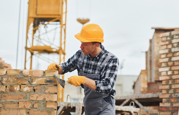 Posa di mattoni Lavoratore edile in uniforme e equipaggiamento di sicurezza ha un lavoro sulla costruzione