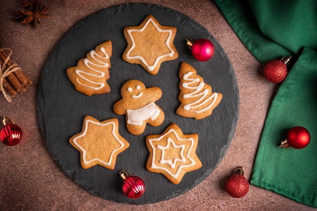 Posa piatta con biscotti di pan di zenzero al forno piccanti fatti in casa serviti con palline di natale rosse sul tavolo