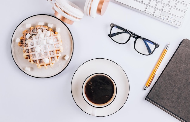 Posa piatta di waffle belgi con marshmallow e cuffie da caffè bicchieri da tastiera su sfondo bianco Vista dall'alto Concetto minimo