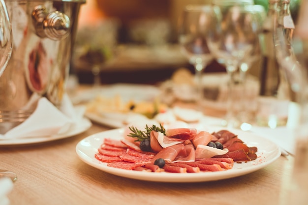 Posate, antipasti, sputacchiera e bicchieri sul tavolo di legno nel ristorante