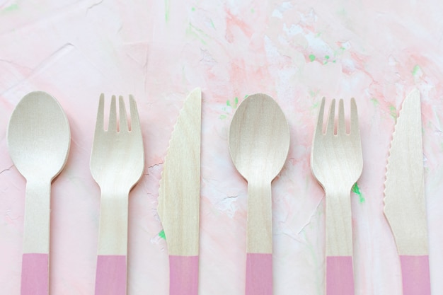 Posate di legno usa e getta eco friendly su sfondo rosa, molti cucchiai, coltelli e forchette posate. Concetto di rifiuti zero, riciclaggio. Alternativa senza plastica per la protezione dell'ambiente. Copia spazio