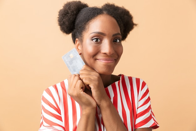 Positiva donna afroamericana sorridente e tenendo la carta di credito, isolata