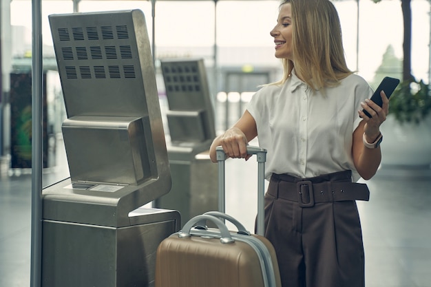 Positiva felice giovane donna che indossa abiti ufficiali mentre va a volare per la conferenza