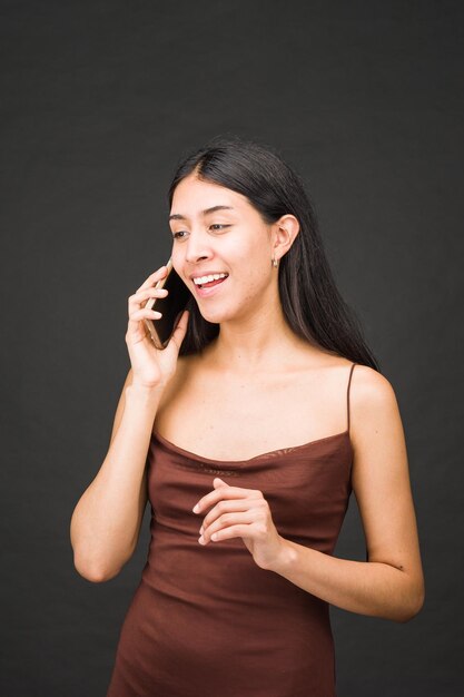 Positiva persona amichevole e allegra con il cellulare giovane ritratto di donna latina bellissima bruna