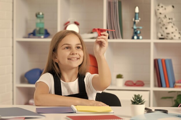 Positivo gioco da bambini con aereo di carta in aula scolastica