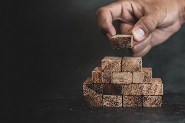 Posizionare a mano la pila di blocchi di legno nel gradino della scala a piramide