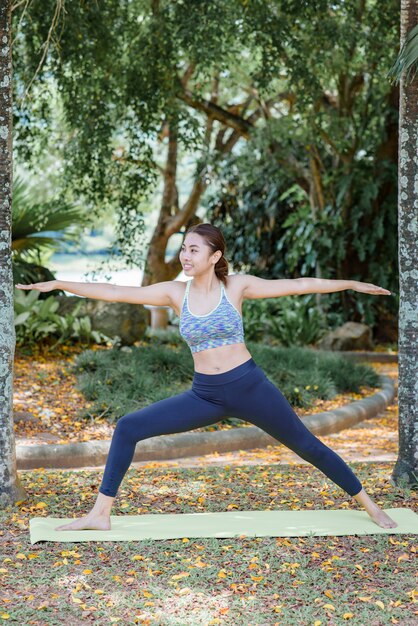 Posizione di pratica di yoga della donna asiatica nel parco