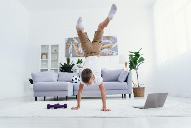 Posizione ginnastica di equilibrio di acrobatica del ragazzo felice isolata su fondo bianco