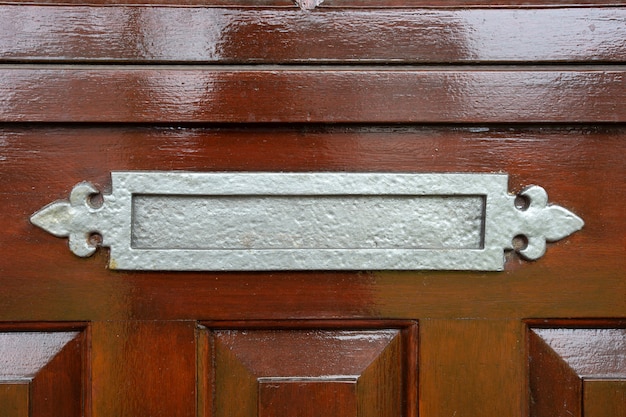 Postbox lucido del metallo su una porta di legno antiquata marrone, primo piano classico di progettazione