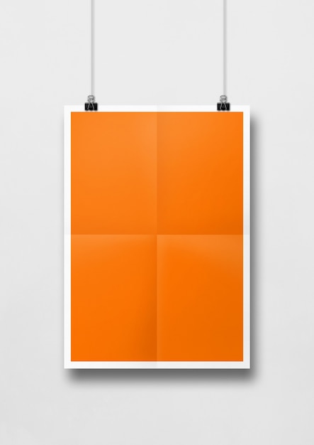 Poster arancione piegato appeso a una parete bianca con clip.