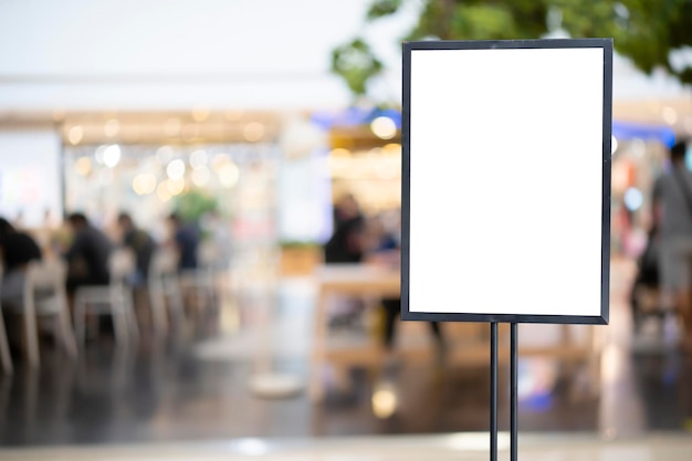 Poster bianco mockup con cornice nera davanti allo sfondo sfocato del ristorante del caffè per la promozione di spettacoli o regali