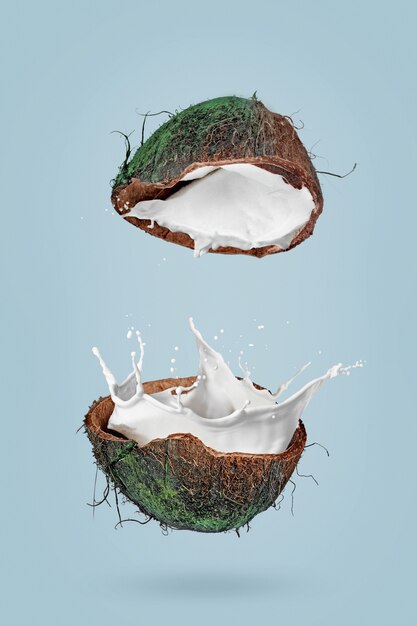 Poster con immagine di metà della noce di cocco e spruzzi di latte su sfondo blu