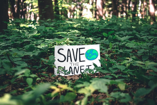 Poster con la scritta salva il pianeta nella foresta tra le piante