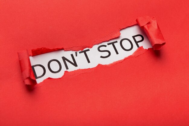 Poster motivazionale con frase Dont stop che appare dietro carta rossa strappata. Concetto di ispirazione e supporto, spazio di copia