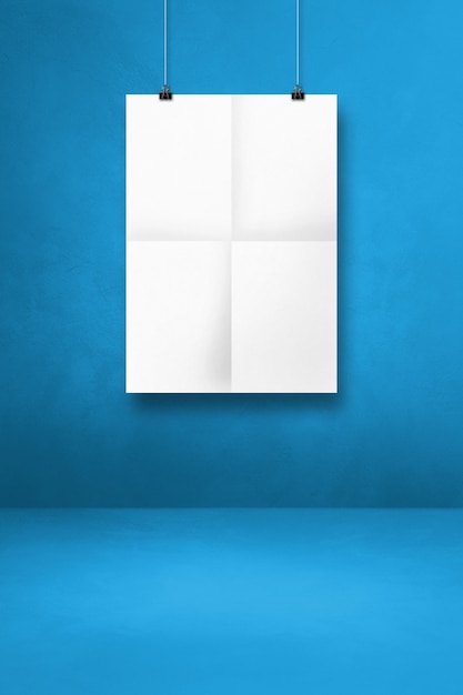 Poster piegato bianco appeso a una parete blu con clip. Modello di mockup vuoto