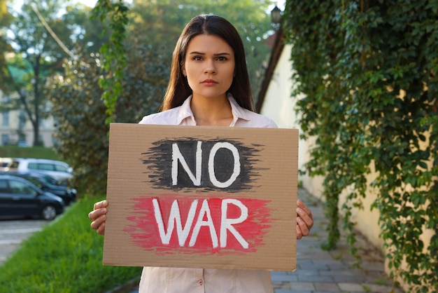 Poster triste della holding della donna con le parole nessuna guerra sulla via della città