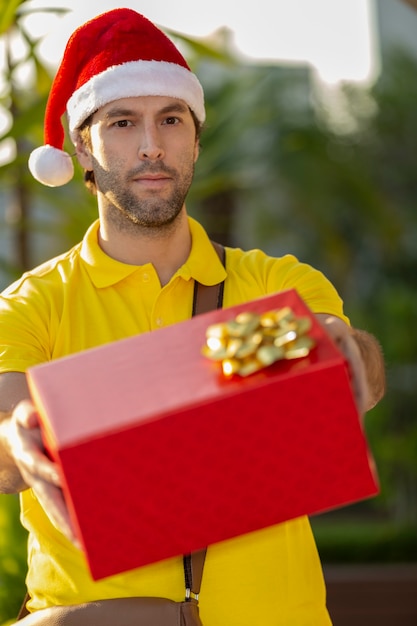 Postino brasiliano vestito da Babbo Natale che consegna un regalo. Acquisto online in fase di consegna.