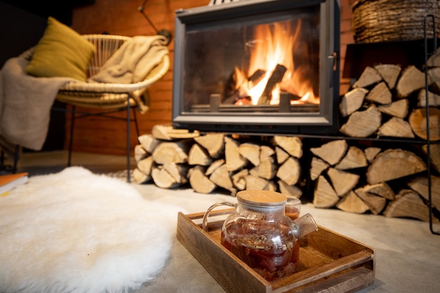 Posto accogliente accanto al caminetto con legna da ardere, bevanda calda e pelle di pecora in un bellissimo interno in stile loft