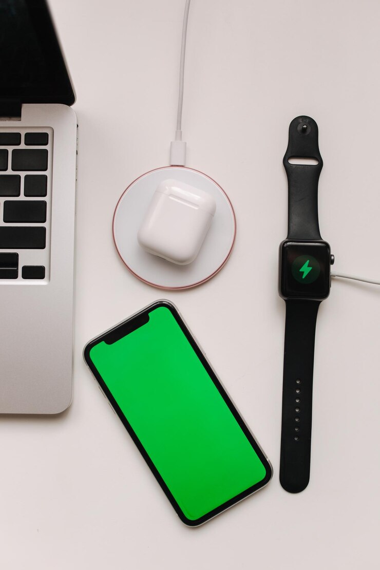 Posto di lavoro con laptop sul tavolo e dispositivi ricarica wireless di smartwatch e wireless