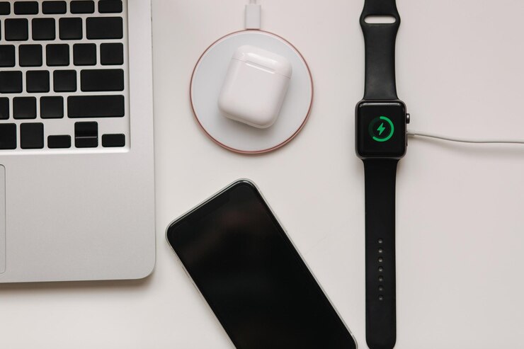 Posto di lavoro con laptop sul tavolo e dispositivi ricarica wireless di smartwatch e wireless