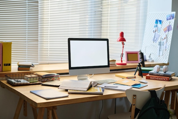 Posto di lavoro con monitor del computer sul tavolo per lo studio online nella stanza degli adolescenti