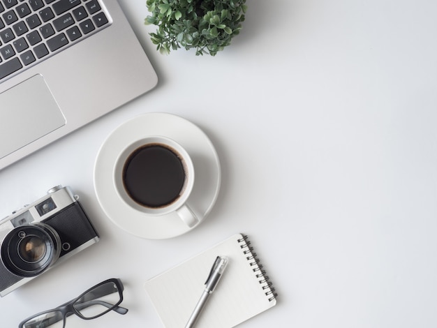 Posto di lavoro con tazza di caffè, taccuino, pianta in plastica e tastiera