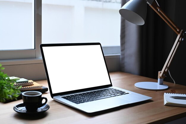 Posto di lavoro confortevole con tazza da caffè per computer portatile aperto e pianta in vaso