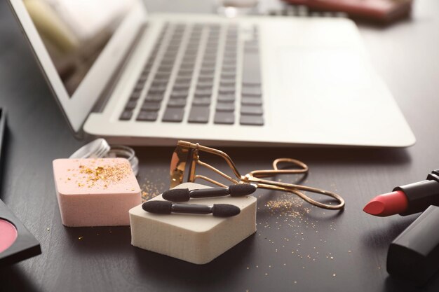 Posto di lavoro confortevole del blogger di bellezza con cosmetici e laptop moderno sul tavolo
