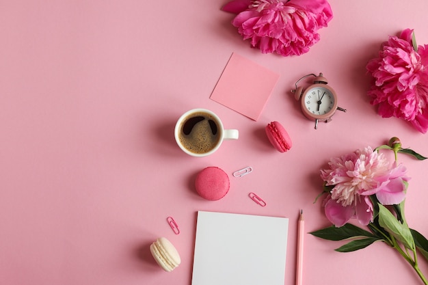 posto di lavoro femminile con blocco note matita sveglia fiori di peonia foglietti adesivi caffè macarons