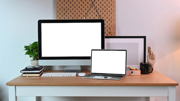 Posto di lavoro moderno con computer e laptop mock up con schermo bianco