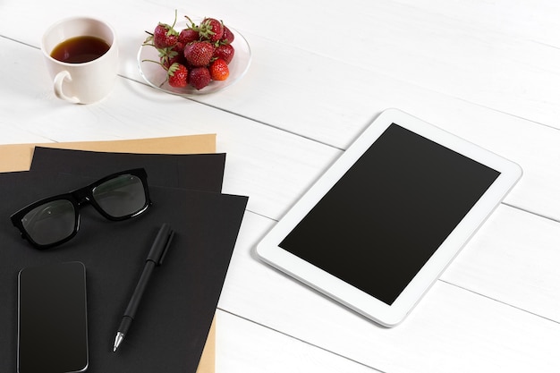 Posto di lavoro moderno con computer tablet digitale e telefono cellulare, tazza di caffè, penna e foglio di carta vuoto. Vista dall'alto e copia spazio per il testo