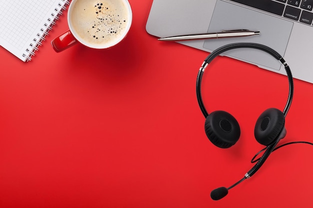 Posto di lavoro rosso dell'ufficio con la tazza di caffè e l'auricolare