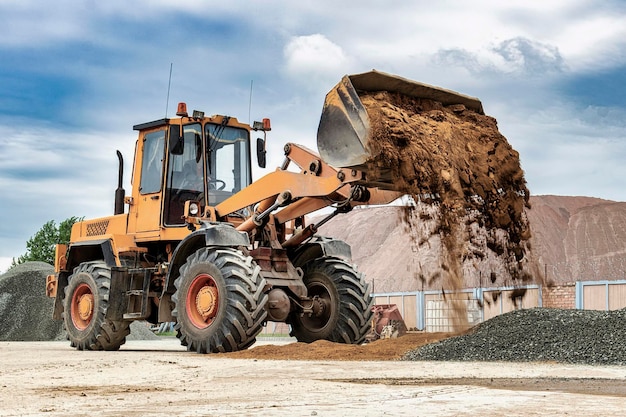 Potente caricatore a ruote o bulldozer contro il cielo Caricatore versa sabbia dal secchio