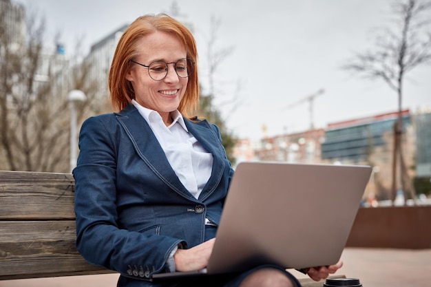 Potente donna d'affari che si fa carico all'esterno con il suo computer portatile