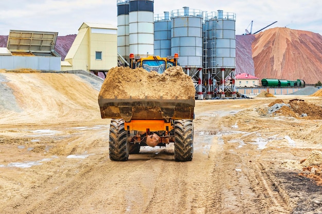 Potente pala gommata o bulldozer che lavora in una cava o in un cantiere Caricatore con un secchio pieno di sabbia Potente attrezzatura moderna per lavori di sterro