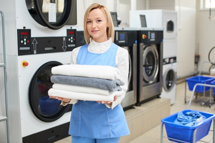 Potret pekerja laundry dengan latar belakang pakaian yang digantung di dry cleaning