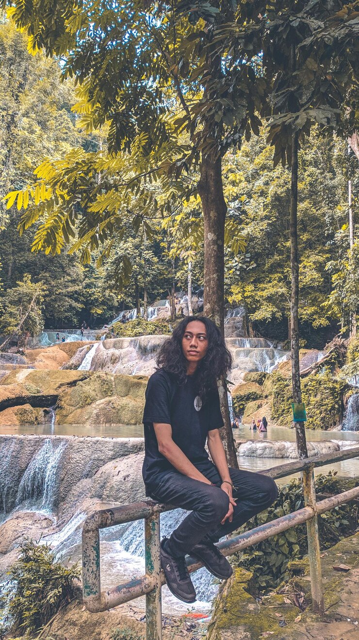 Photo potret pria muda berdiri di depan pepohonan