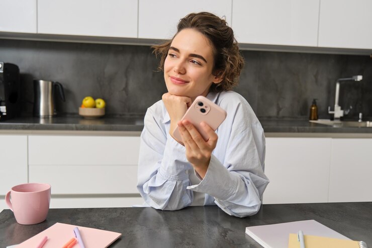 Photo potret wanita cantik tersenyum duduk di rumah dengan smartphone menggunakan aplikasi ponsel untuk memesan