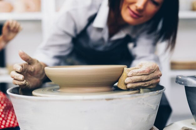 Potter femmina che fa ceramica di argilla su una ruota di rotazione.