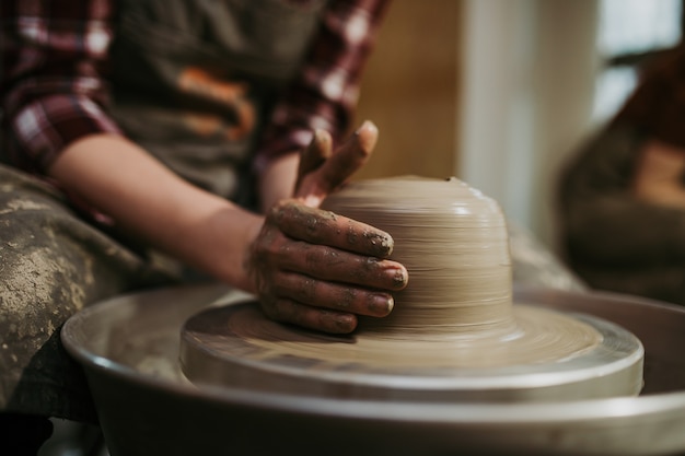 Potter femmina che fa ceramiche di argilla su una ruota di rotazione.