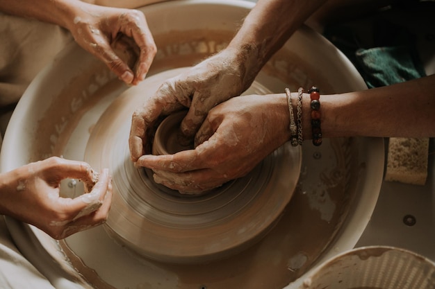 Potter insegna a una ragazza adolescente a lavorare con la ruota di ceramica vista in alto da vicino