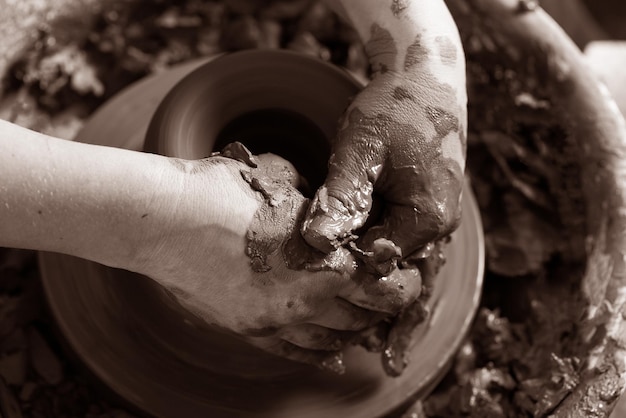 Potter mani che fanno in argilla sul tornio di ceramica Potter fa sul piatto di argilla del tornio di ceramica