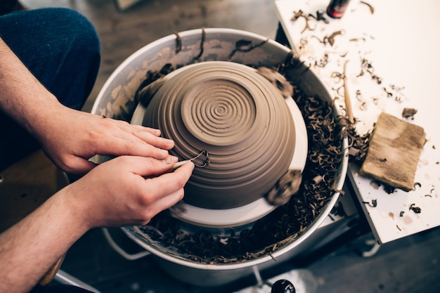 Potter maschio che fa ceramiche di argilla su una ruota di rotazione.