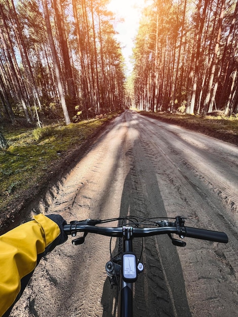 POV di andare in bicicletta Primo piano del manubrio in bicicletta con sfondo di strada sterrata forestale