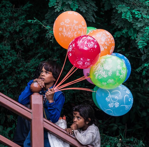 Poveri bambini che vendono più palloncini colorati e guardano qualcuno per la vendita