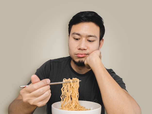 Povero uomo asiatico sentirsi noioso con lo stesso vecchio noodle istantaneo.