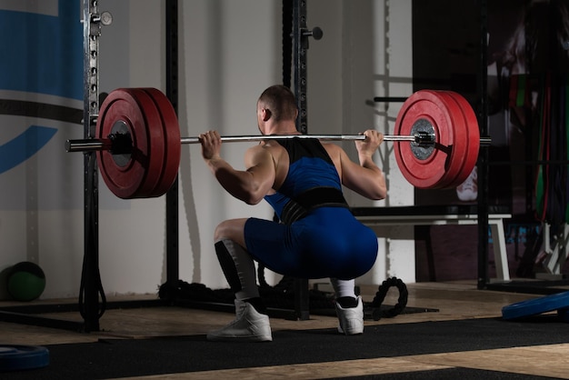 Powerlifter che fa esercizio per le gambe con il bilanciere